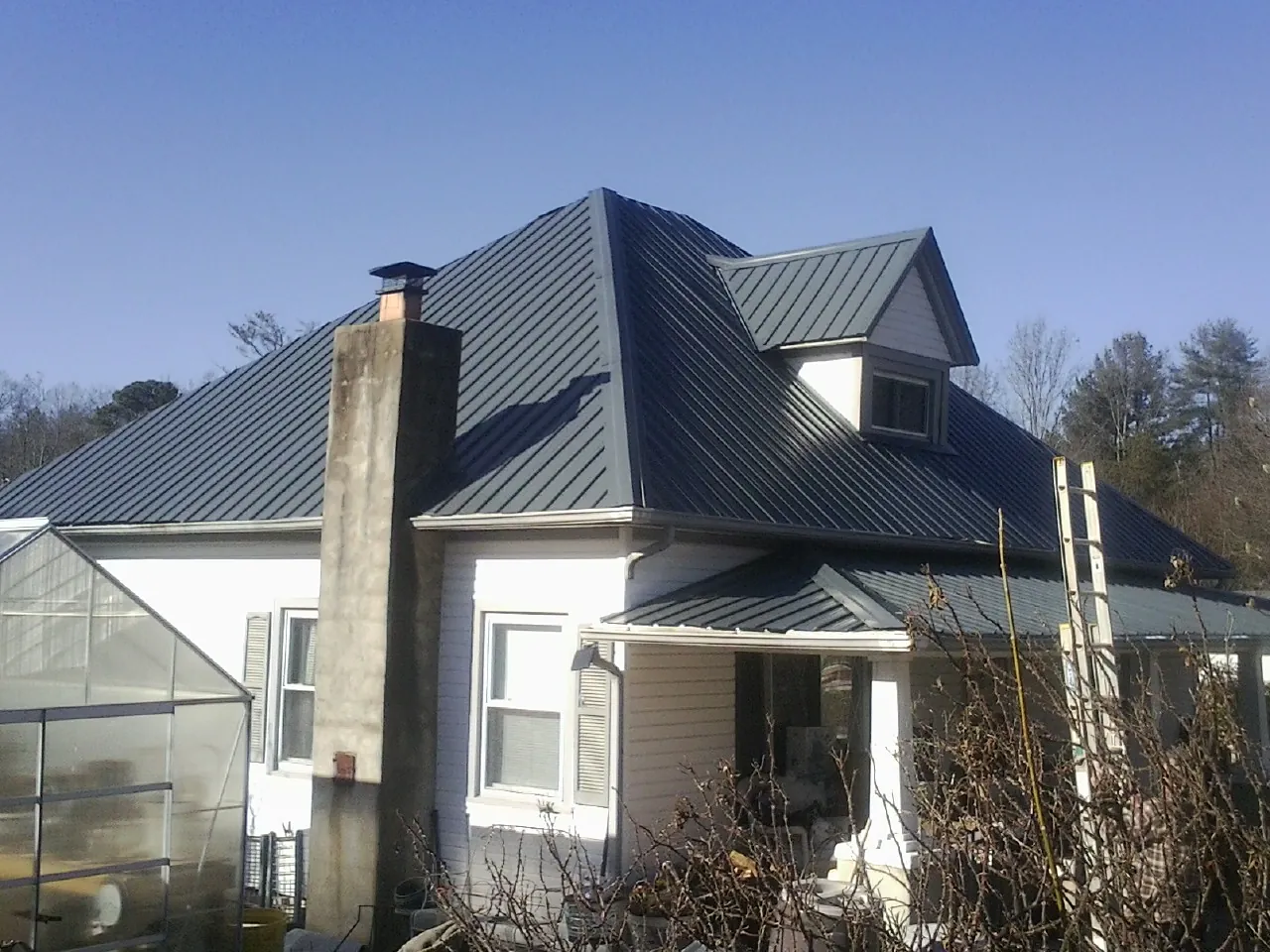 Dark blue standing seam metal roof on a white farmhouse with dormer — Slate & Tile Roof Repair by Roofing Brothers in Chenango Forks