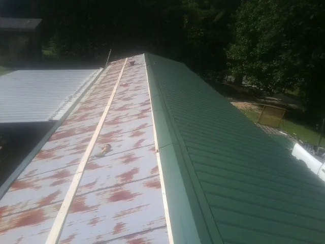 Old rusted panels beside newly installed green metal roofing — Wind Damage Roof Repair by Roofing Brothers in Chenango Forks