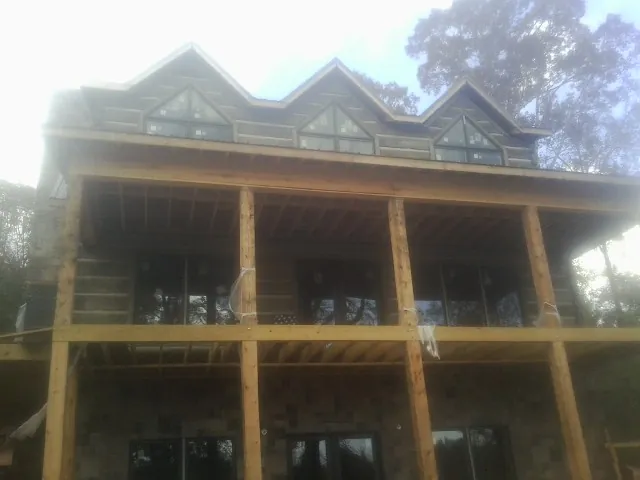 Dormers and porch framing on a large log home under construction — Roof Coating work by our crew in Chenango Forks