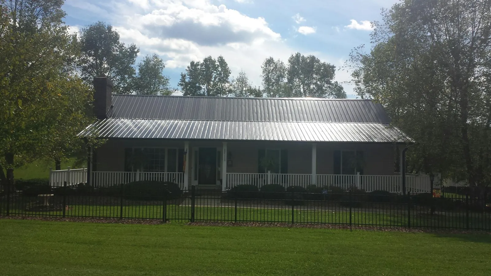 Gray metal roof on a brick ranch with a full width front porch — Gutter Guard Installation work by our crew in Chenango Forks
