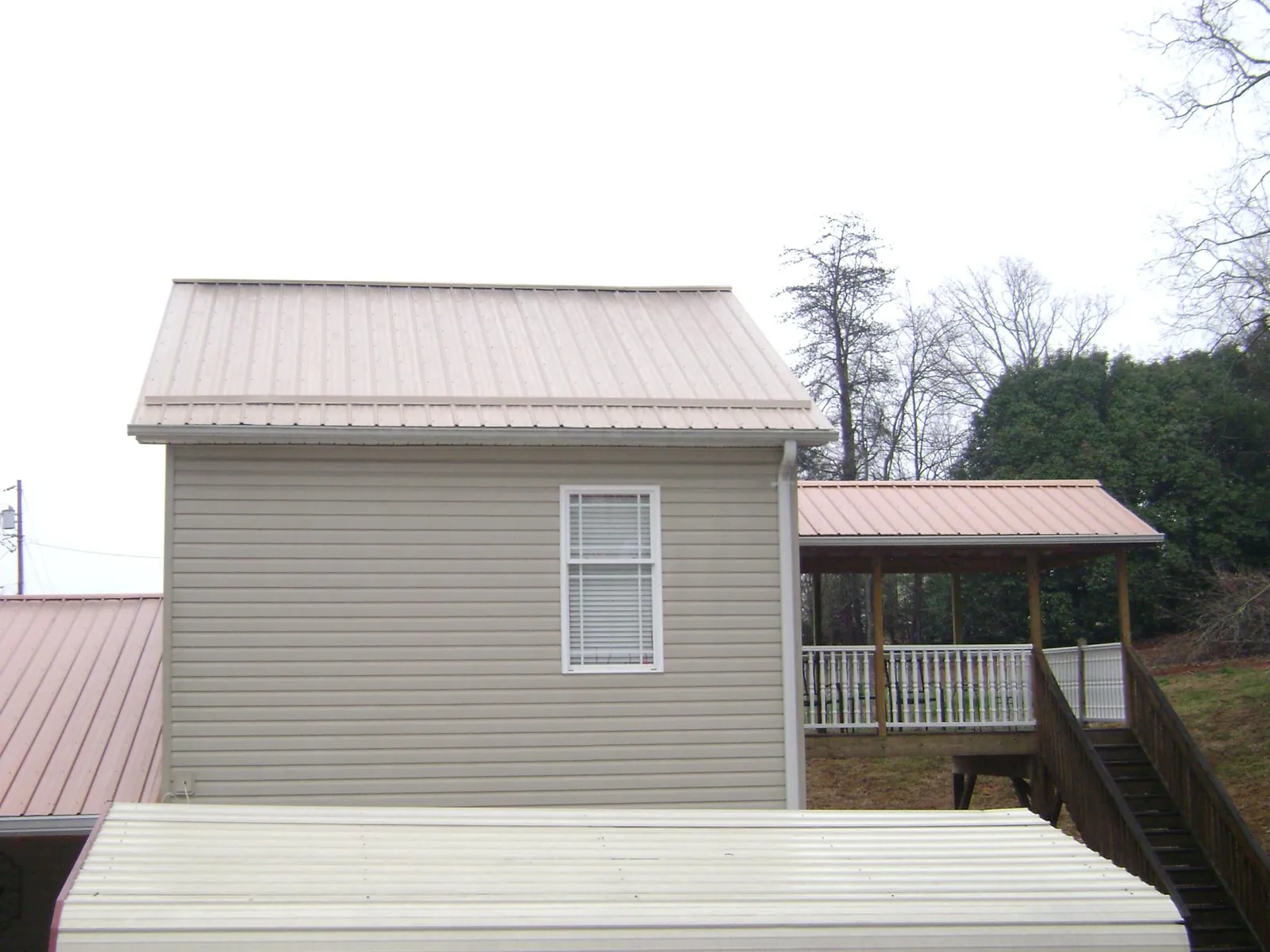 Tan metal roofs on a two story addition and attached porch, from a Roof Replacement job in Chenango Forks
